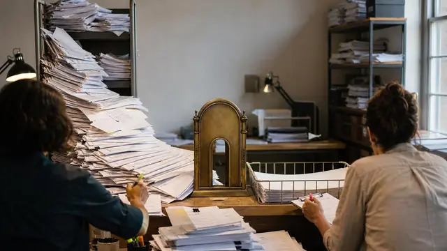 A moderation desk with anonymous reviewers filtering a flood of paper manuscripts through a narrow gate, showing overflow and bottleneck.